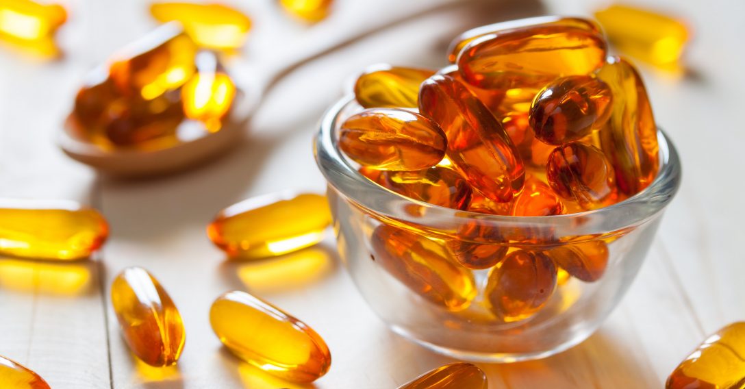 Fish oil capsules on wooden background and texture, vitamin D supplement, selective focus