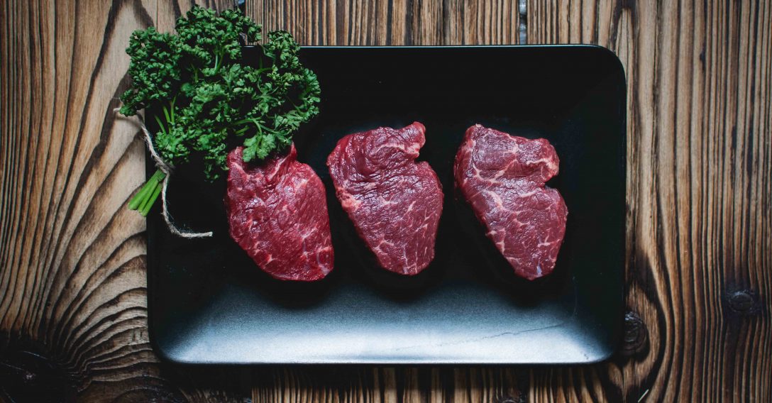 Raw beef steaks on a black plate