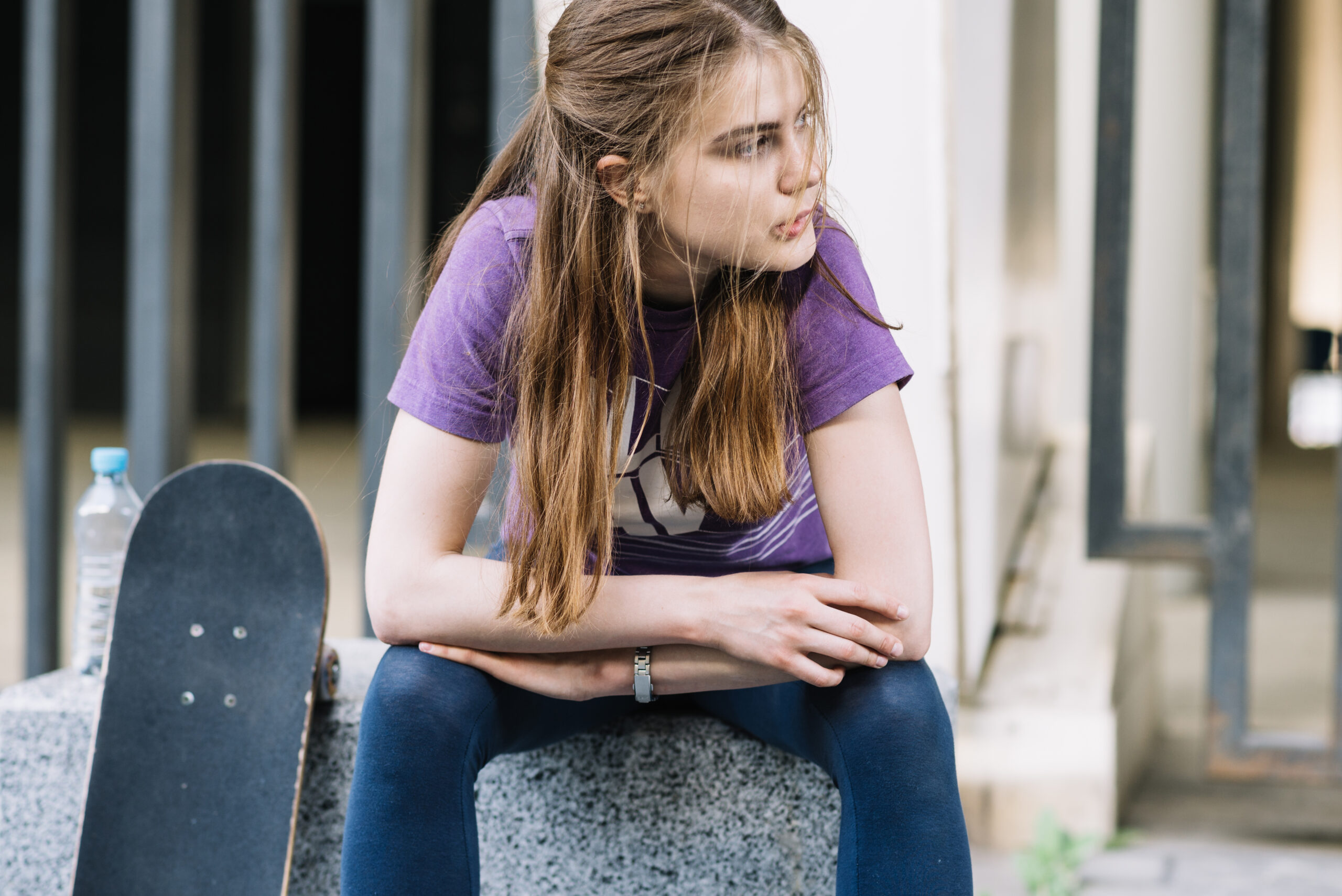 skateboarder-girl-sits-with-her-skateboard-biting-her-lip