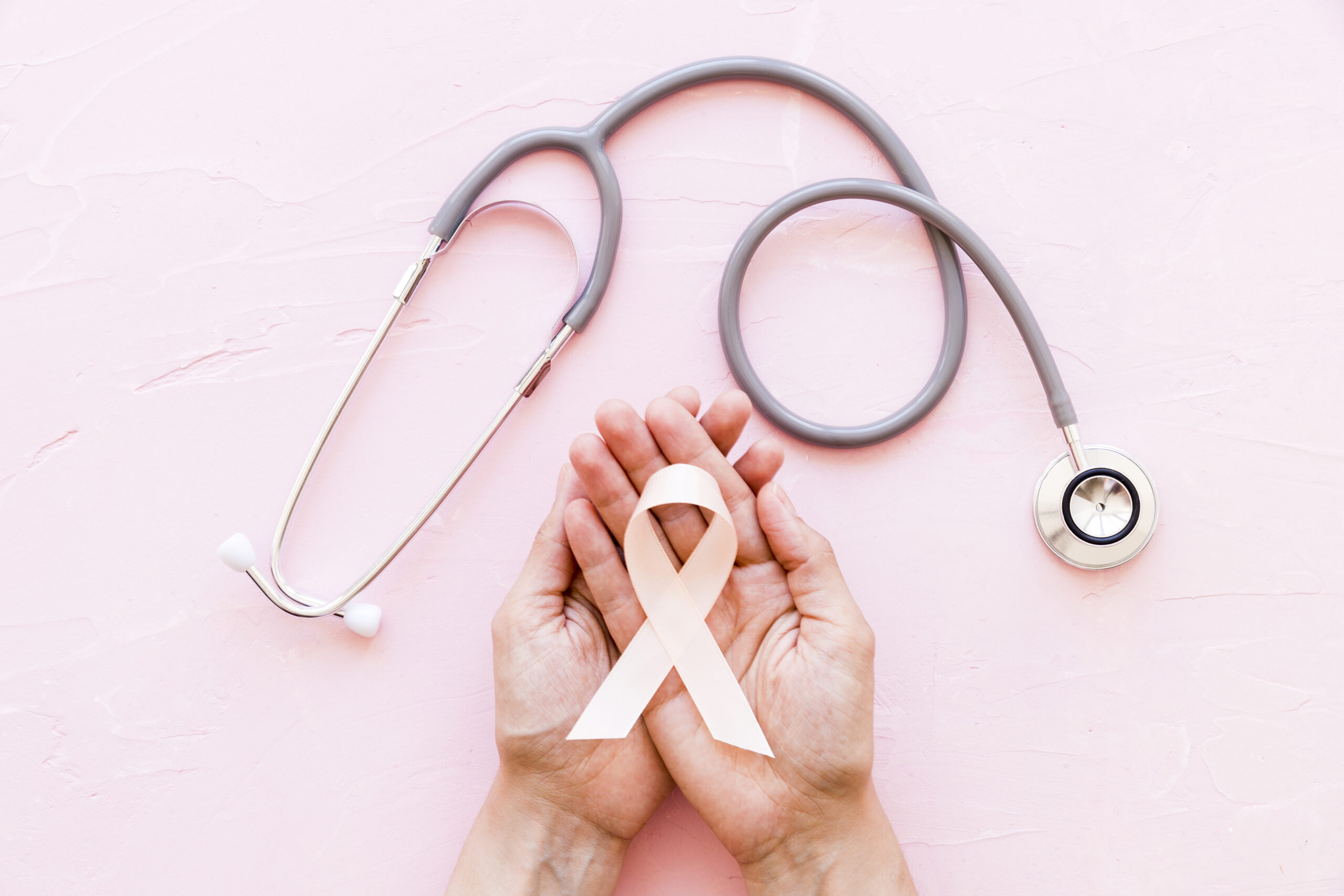 white-awareness-ribbon-two-hands-with-stethoscope-pink-background