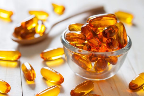 Fish oil capsules on wooden background and texture, vitamin D supplement, selective focus