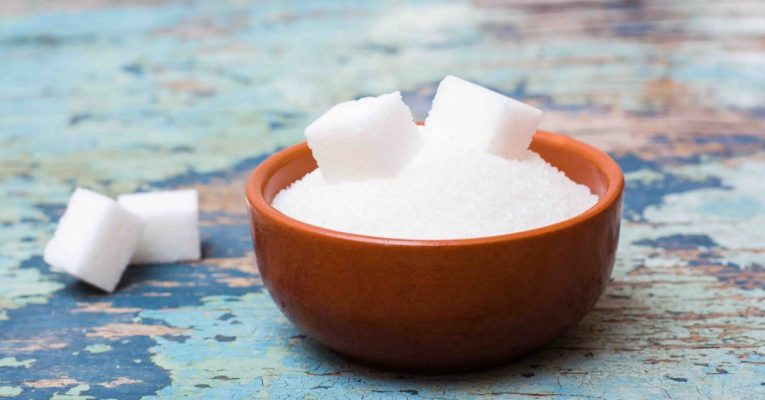 Sugar granulated and refined sugar in a bowl on a wooden table